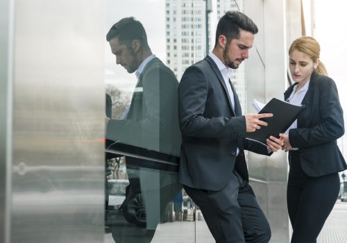 businessman-businesswoman-looking-documents-standing-outside-office